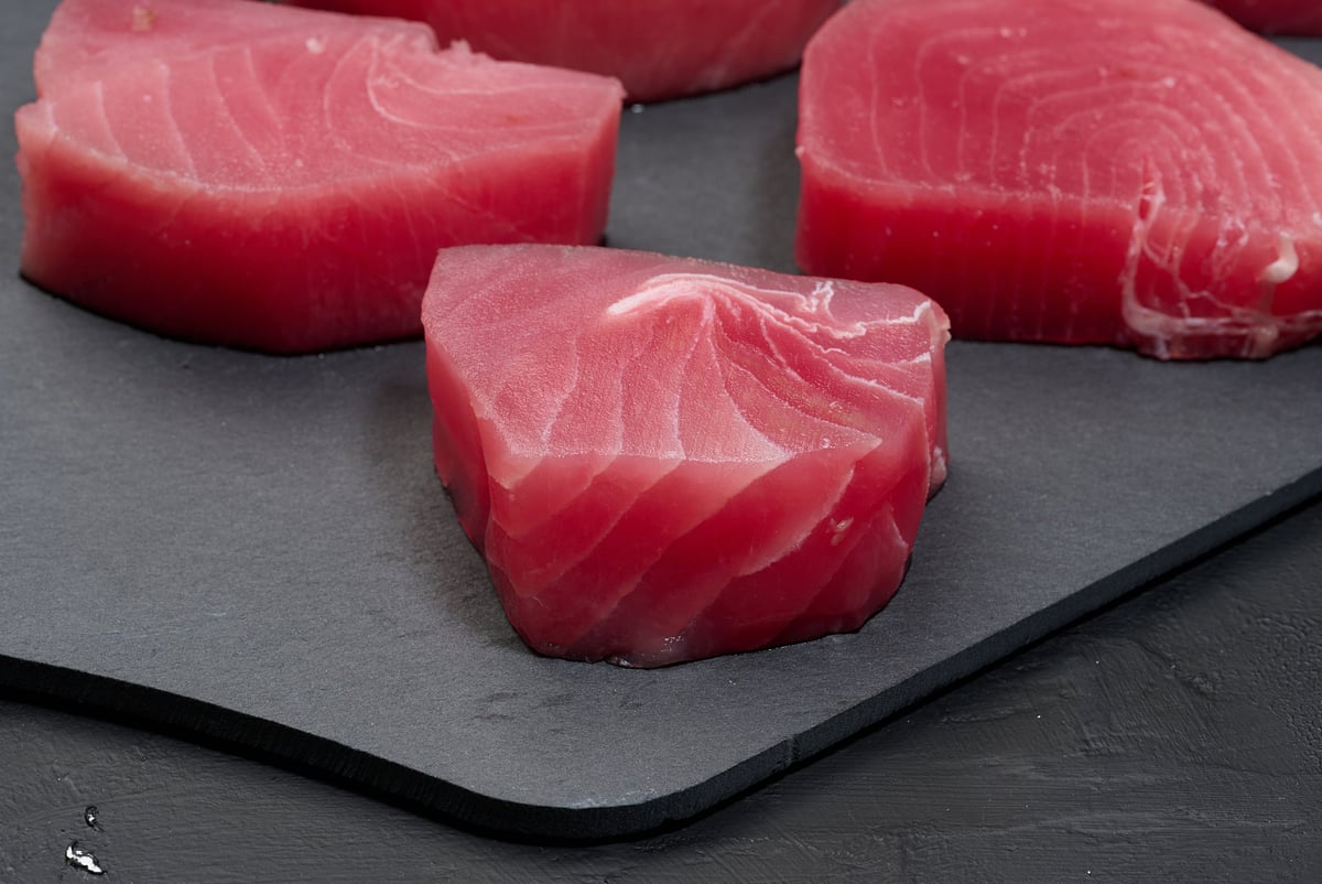 Raw tuna pieces on a black board