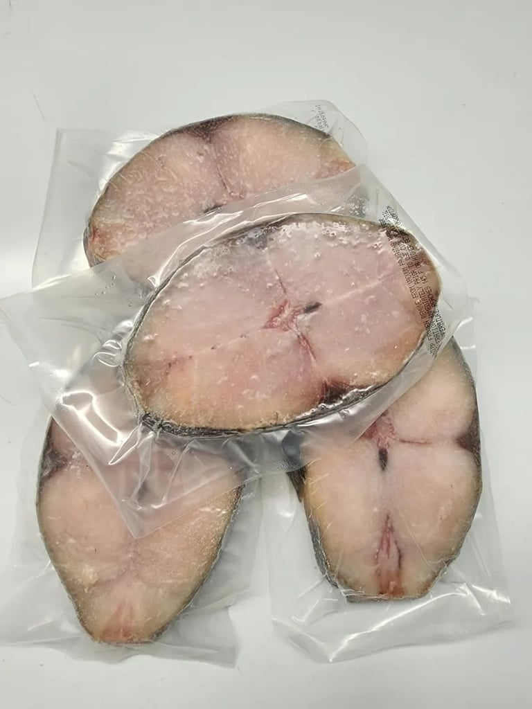 Four raw scallops in clear plastic vacuum-sealed packaging on a white background